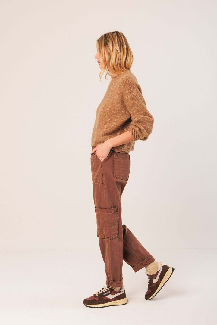 Femme portant un chandail en maille texturée marron et un pantalon cargo, style décontracté pour l'hiver.