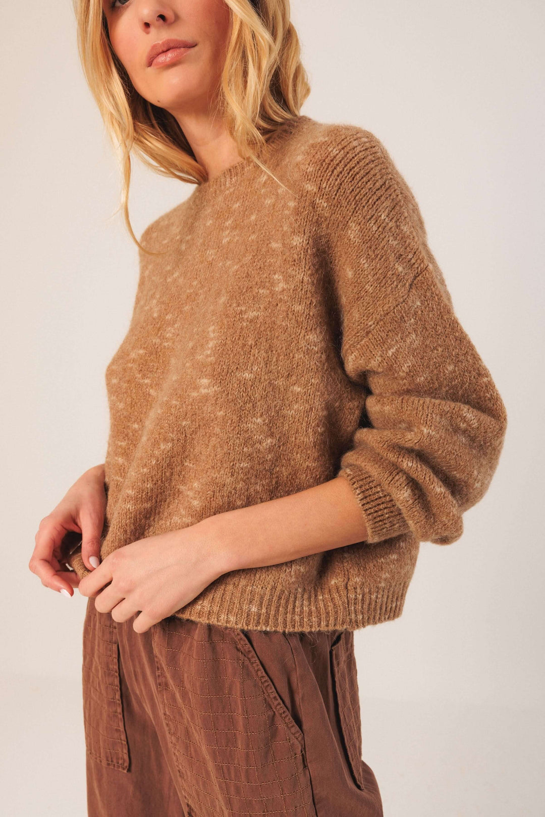 Chandail maille texturée beige à col rond et manches bouffantes, parfait pour un look décontracté en saison froide.