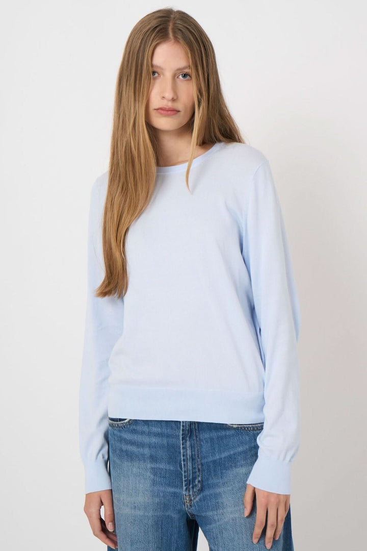 Femme portant un chandail à manches longues bleu clair avec jean, style décontracté et quotidien.