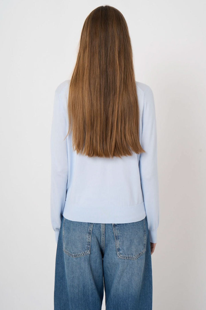 Femme portant un chandail à manches longues bleu, coupe droite, vue de dos avec jean casual, tissu doux et confortable.