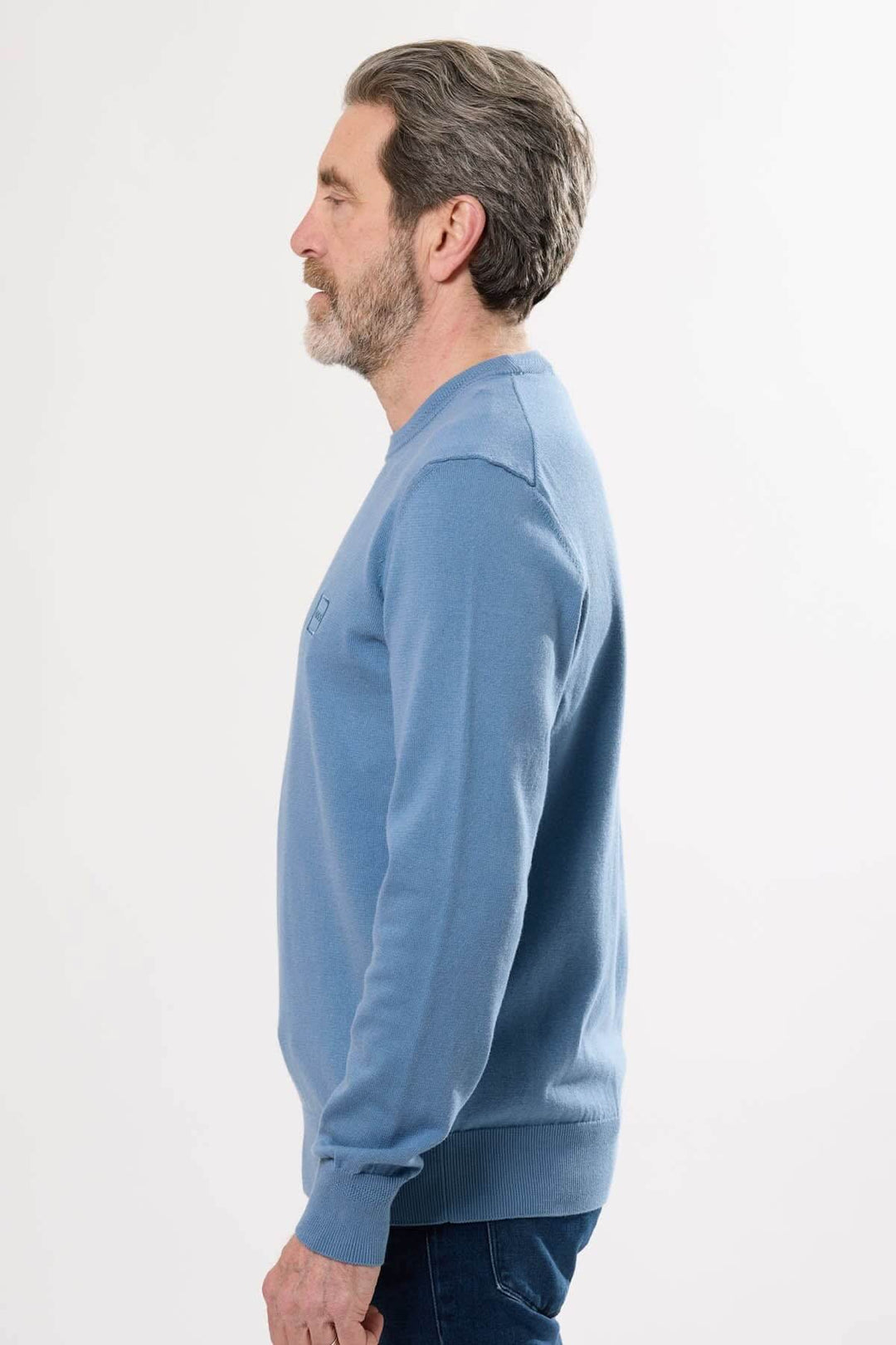 Homme portant un chandail manches longues Hugo Boss en bleu, vue de profil, style élégant et décontracté.