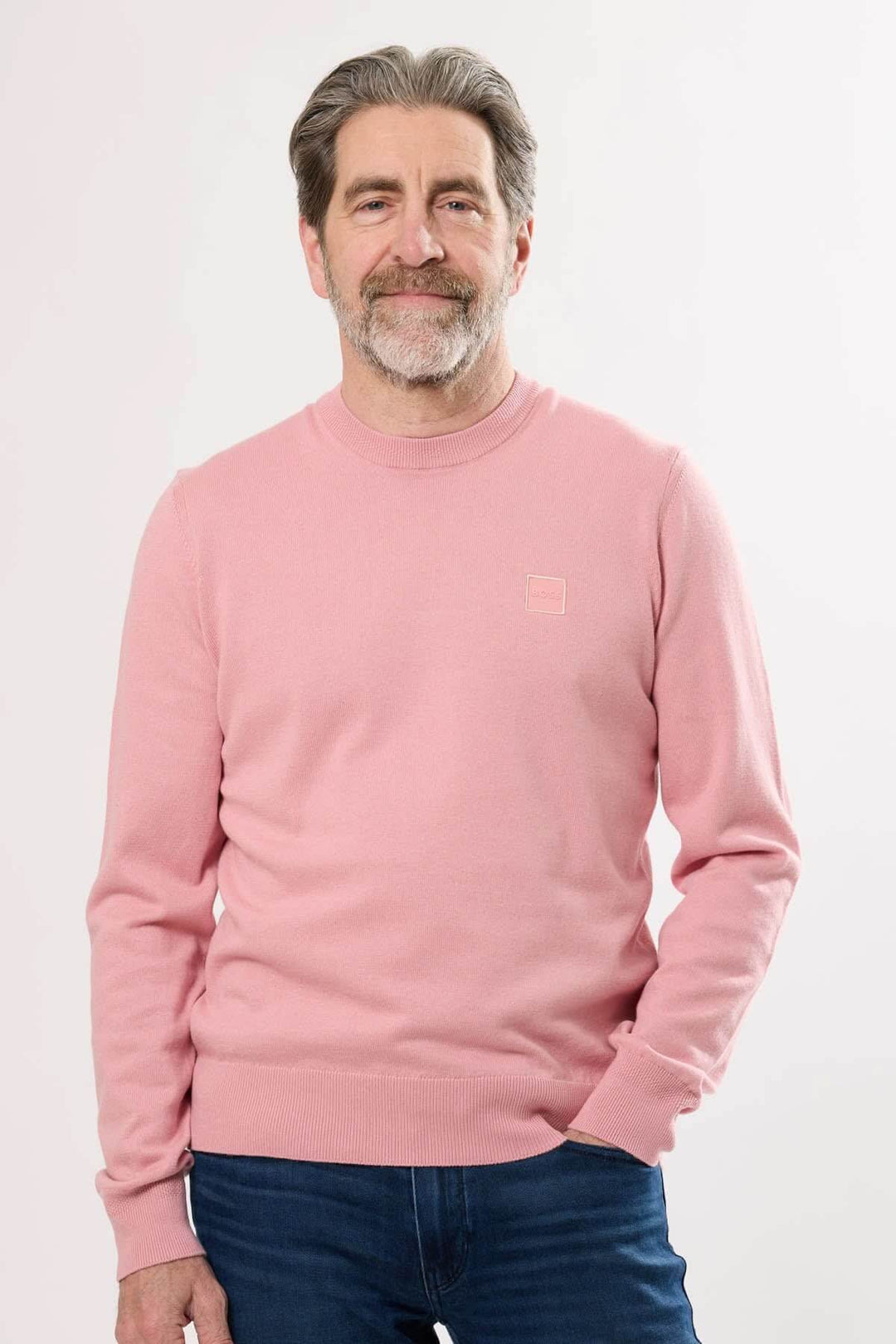 Homme portant un chandail à manches longues Hugo Boss rose avec logo, style décontracté et élégant.