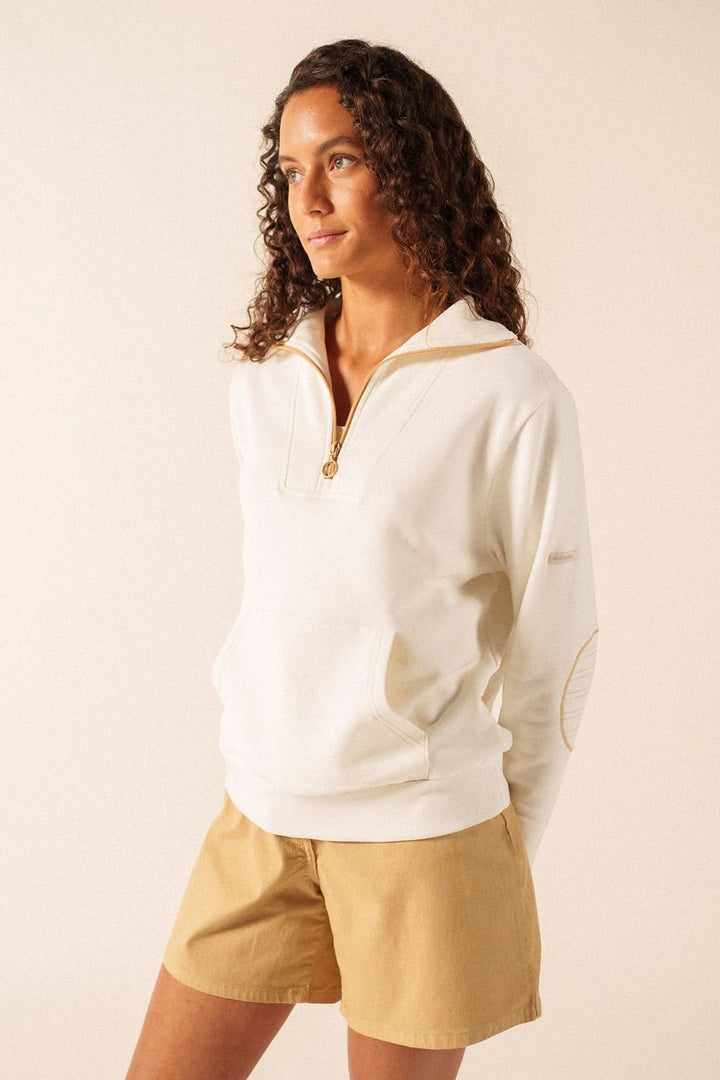 Femme portant un chandail molletonné LOU blanc avec demi-glissière contrastante et coudières surpiquées, style sport-chic.