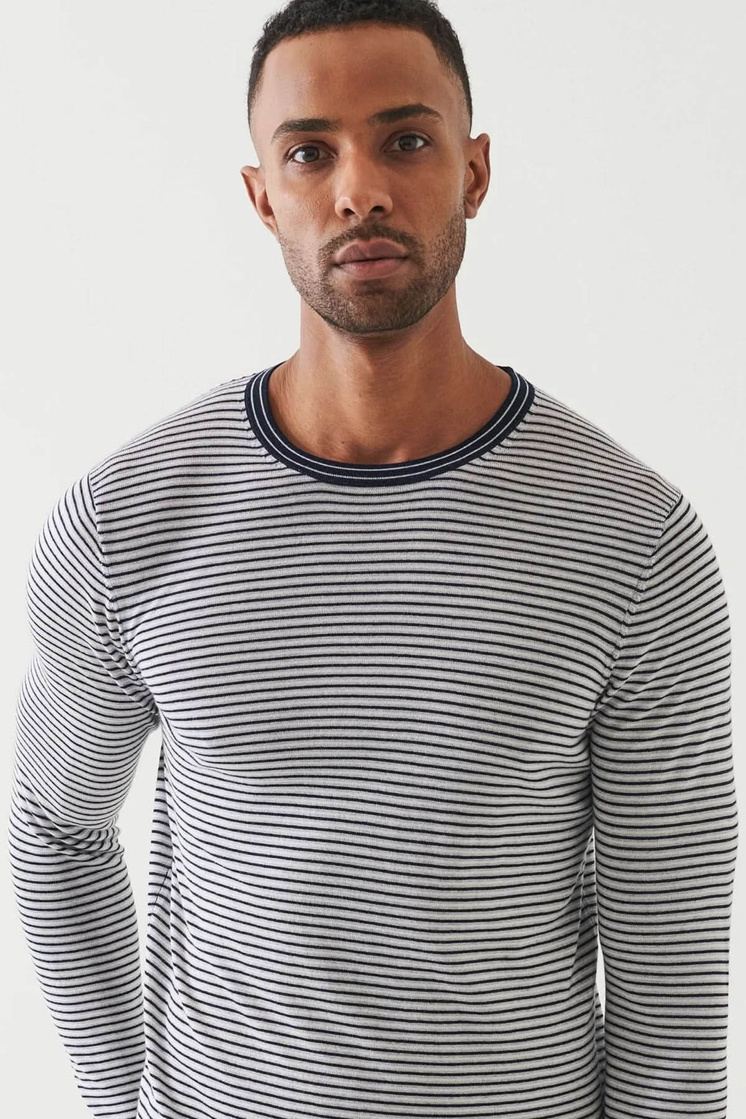 Homme portant un chandail à rayures horizontales, encolure ronde, coupe ajustée et tricot souple.