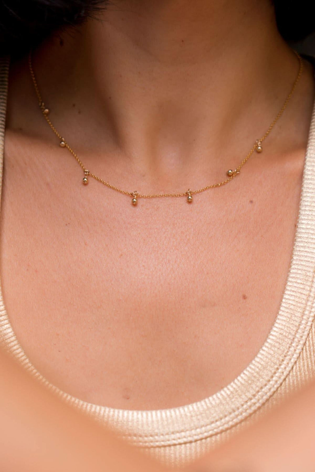 Collier délicat avec des perles, porté sur un cou élégant, ajoutant une touche de sophistication.