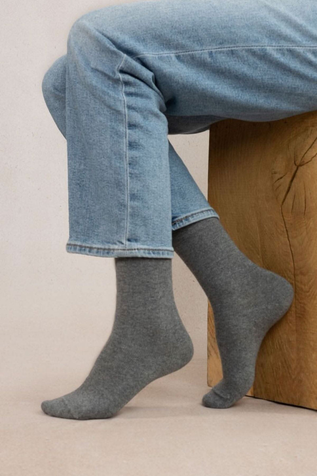 Chaussettes cachemire unies grises portées avec un jeans, ajoutant confort et chaleur pour l'automne-hiver.