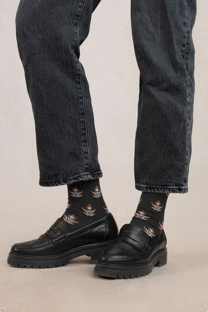 Chaussettes à fleurs noires avec des chaussures noires, parfaites pour l'hiver et confortables.