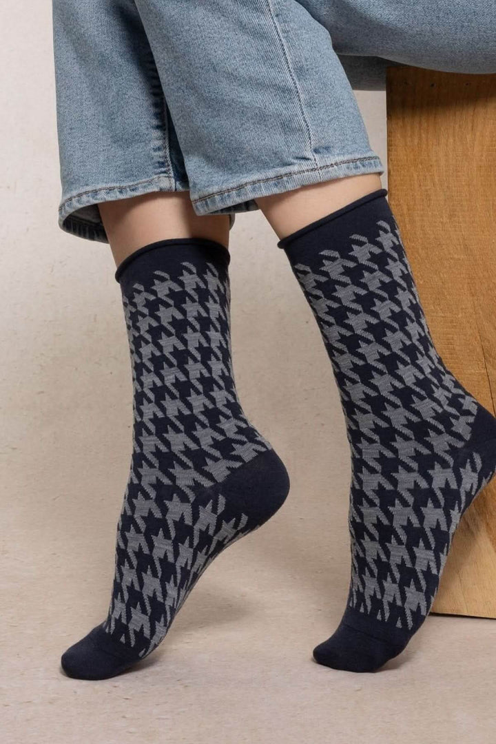 Chaussettes à motif de pied-de-poule en laine et coton, longueur mi-mollet, portées avec un jean pour un style élégant et quotidien.
