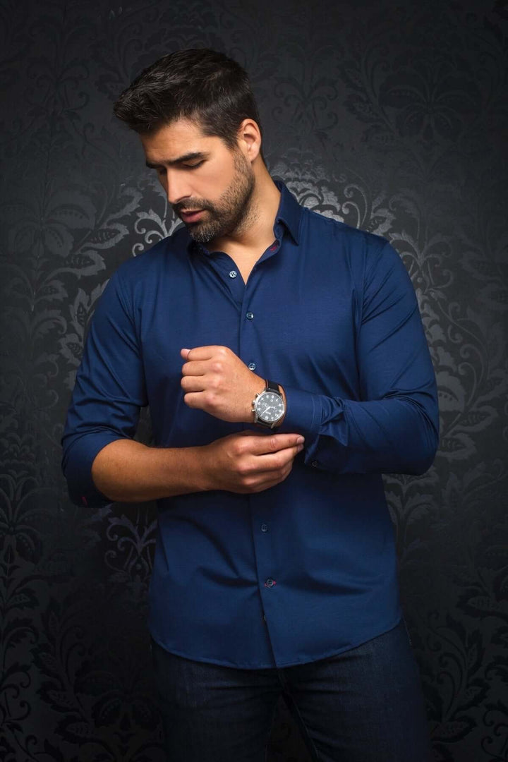 Homme portant une chemise Alexander à manches longues, couleur bleu, avec une montre élégante, sur fond sombre.