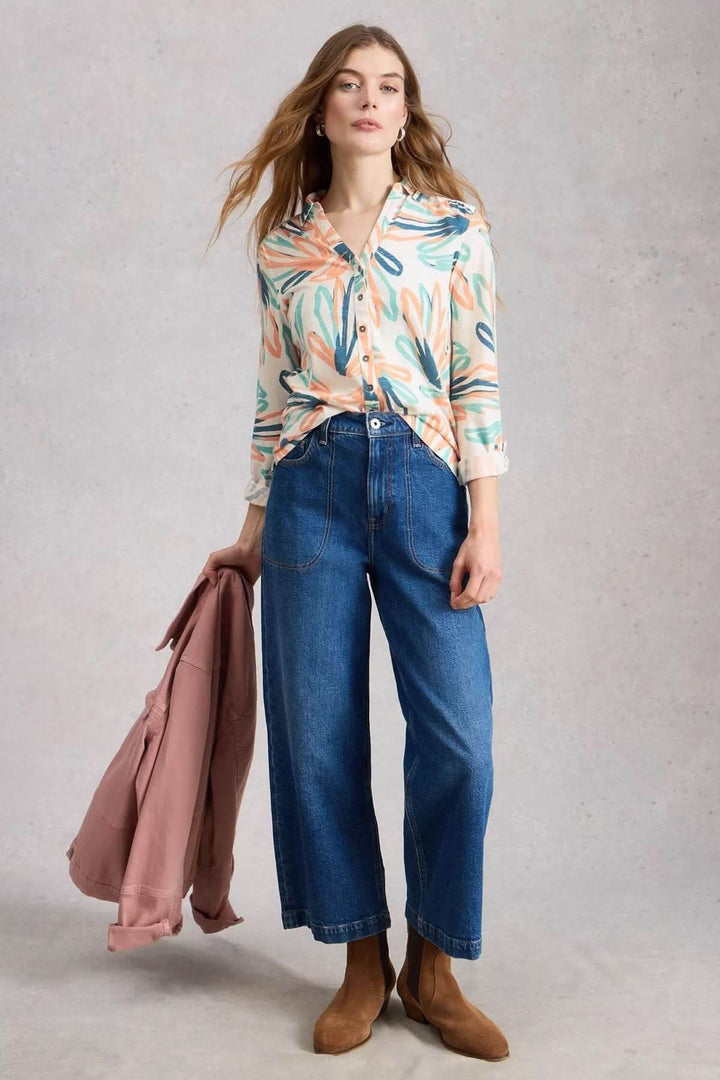 Femme portant une chemise boutonnée col en V manches trois-quarts Annie, avec un imprimé floral et un jean évasé.