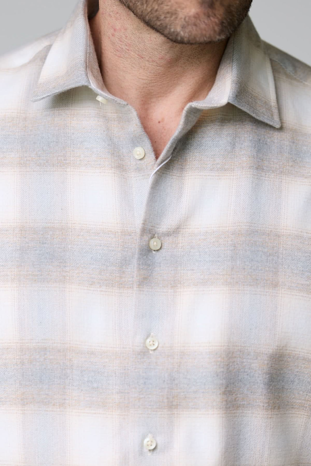 Chemise à carreaux doux en flanelle avec motif subtil, col classique, et boutons nacrés sur fond gris clair.