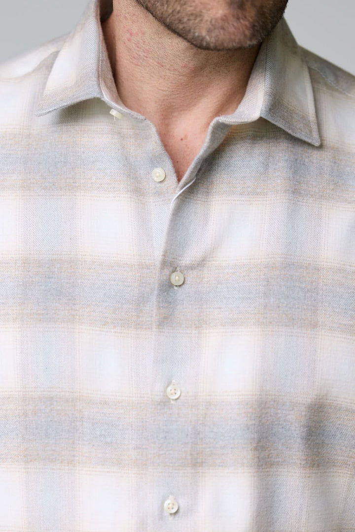 Chemise à carreaux doux en flanelle avec motif subtil, col classique, et boutons nacrés sur fond gris clair.