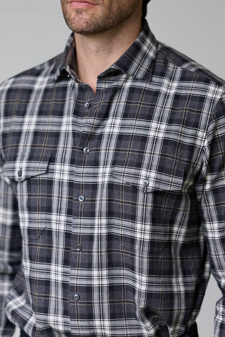 Homme portant une chemise à carreaux en flanelle douce, deux poches à rabat sur la poitrine et boutons ton sur ton pour un style décontracté.