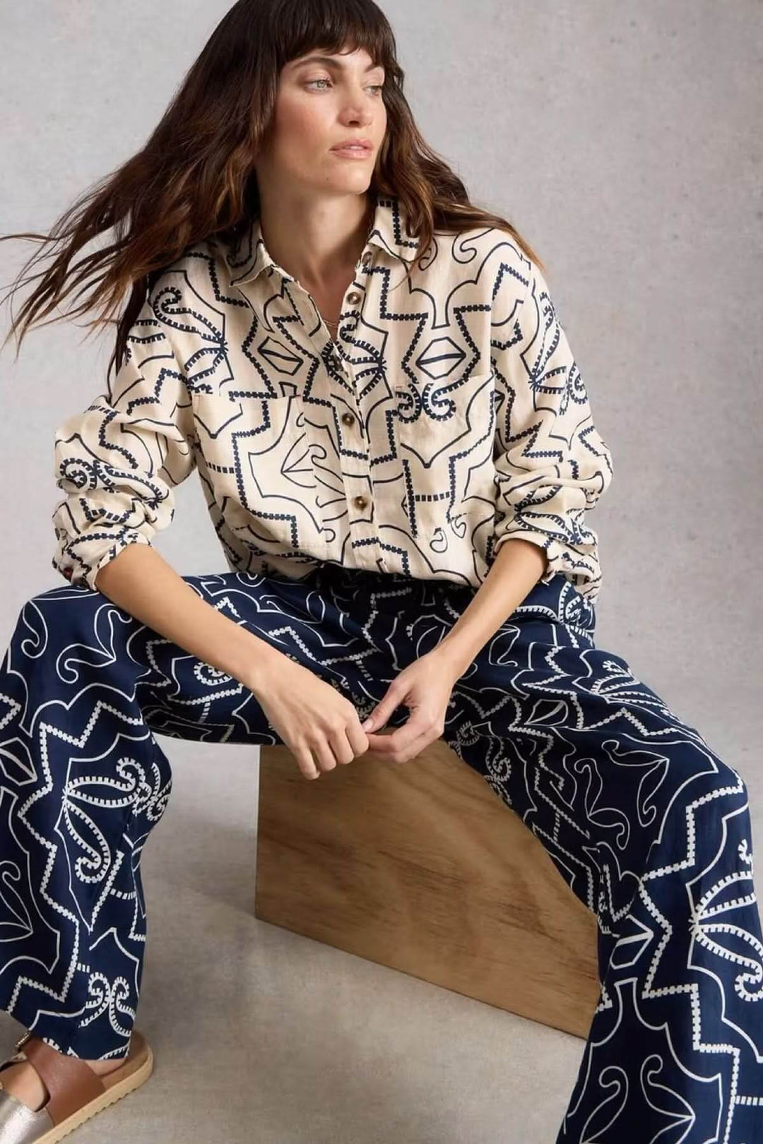 Chemise à col en lin Lydia, coupée droite, imprimée graphique, portée de manière décontractée par un modèle assis.
