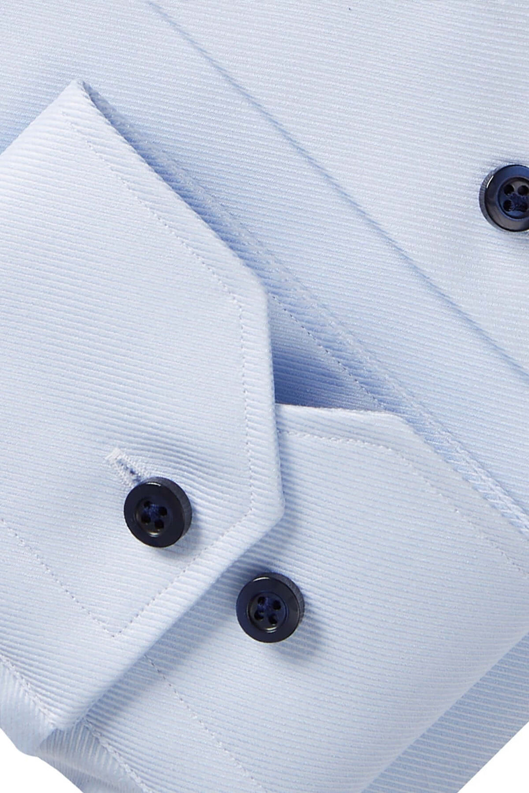 Détail d'une chemise bleue avec col et boutons contrastants, tissu texturé et coupe moderne.