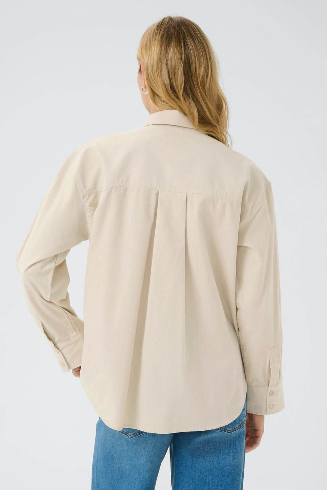 Chemise en corduroy fin Savannas beige vue de dos, portée par une femme avec jeans, soulignant le style décontracté et élégant.