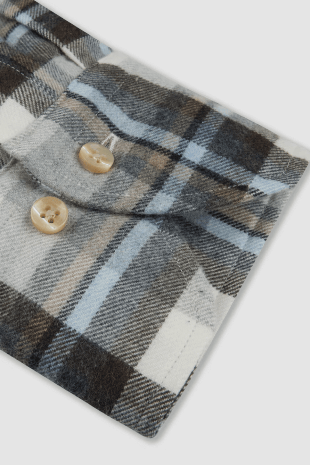 Détail d'une chemise en flanelle à carreaux avec boutons en nacre et col boutonné.