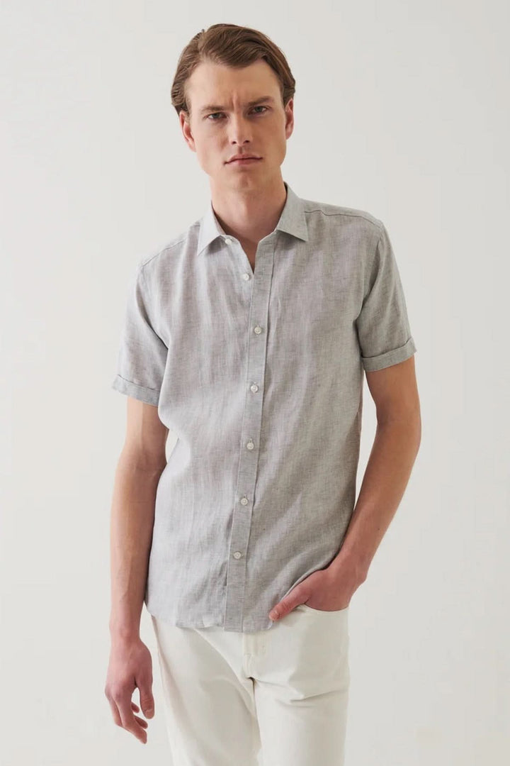 Chemise en lin à manches courtes, style estival, légère et élégante, homme portant un look chic avec pantalon blanc.