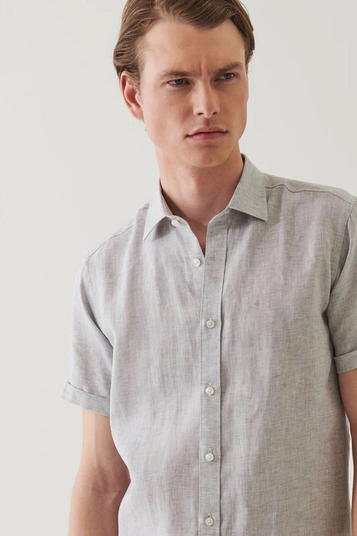 Chemise en lin à manches courtes, couleur chambray, avec col classique et patte de boutonnage.