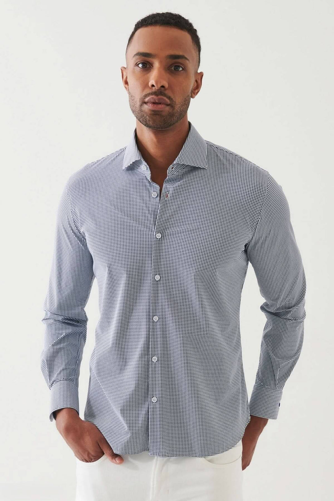 Chemise extensible à motif micro-carreaux, coupe ajustée, col classique, portée par un homme, élégante pour le bureau.