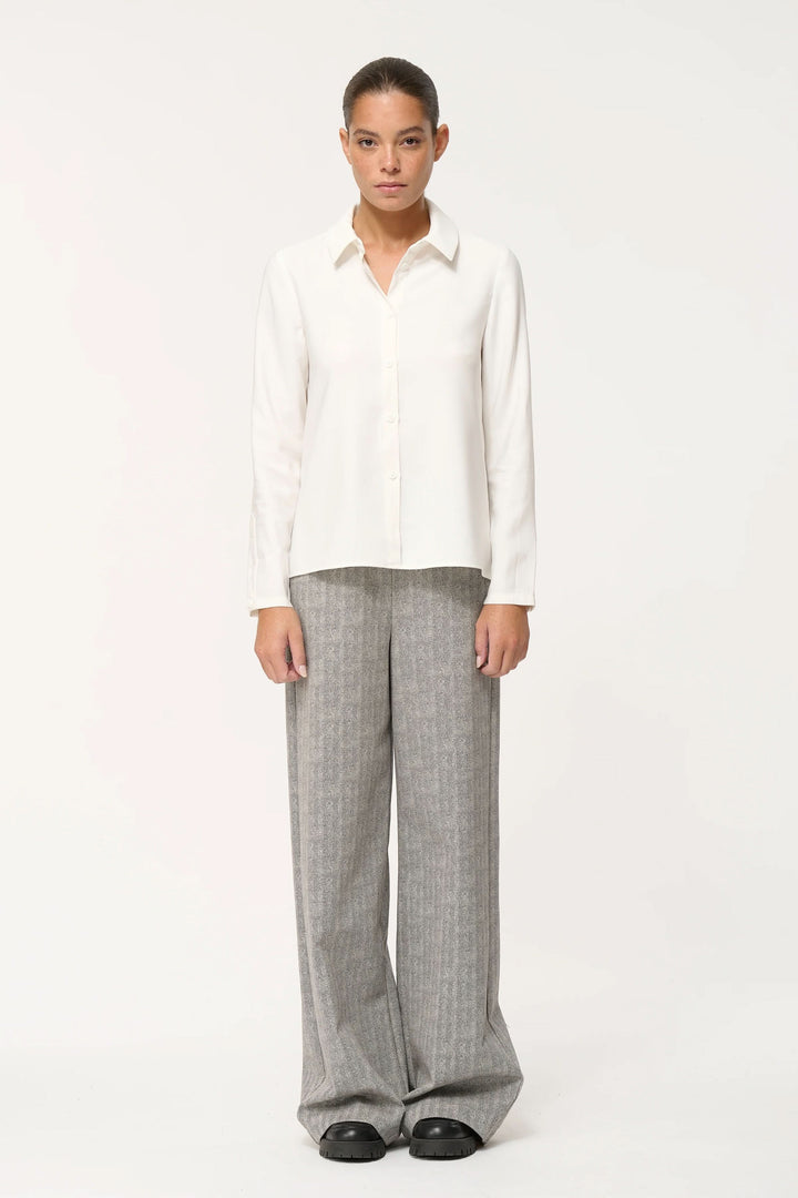 Chemise fluide blanche avec pantalon large rayé, un look élégant et confortable pour le quotidien.