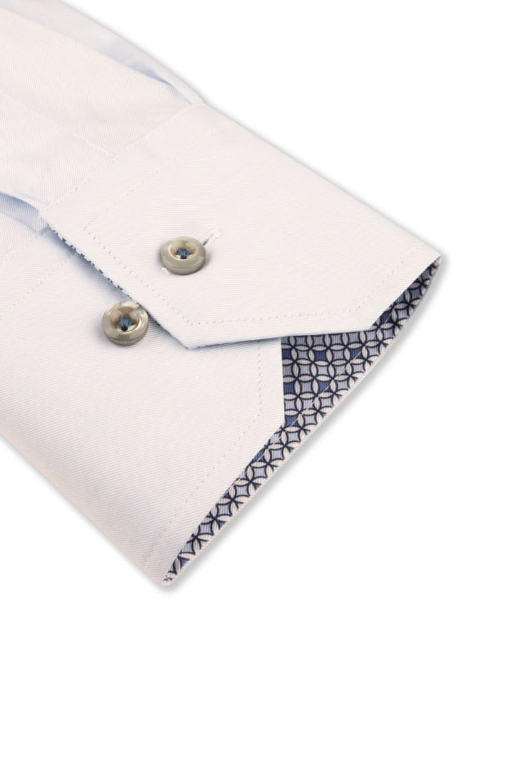 Détail d'une chemise habillée blanche avec poignets contrastés et boutons en nacre véritable.