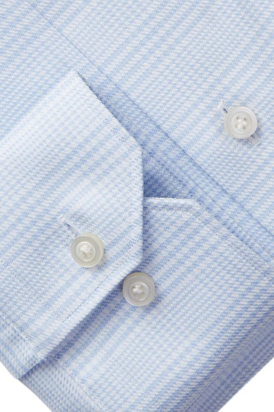 Détail d'une chemise habillée à carreaux bleus avec boutons blancs et poignets ajustables.