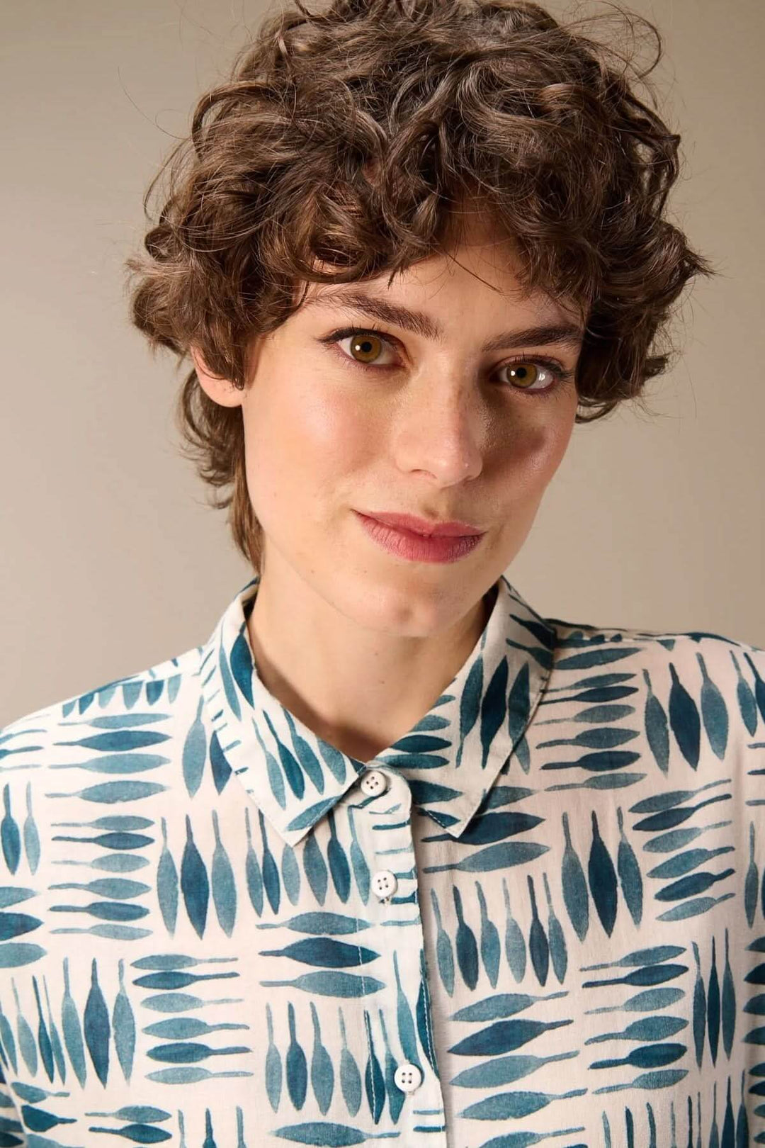 Femme portant une chemise imprimée à manches longues avec motif graphique, col classique et fermeture boutonnée.