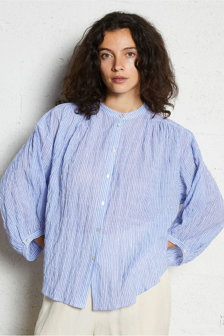 Femme portant une chemise intemporel bleue à rayures, manches longues, et coupe fluide, idéale pour une tenue élégante et confortable.