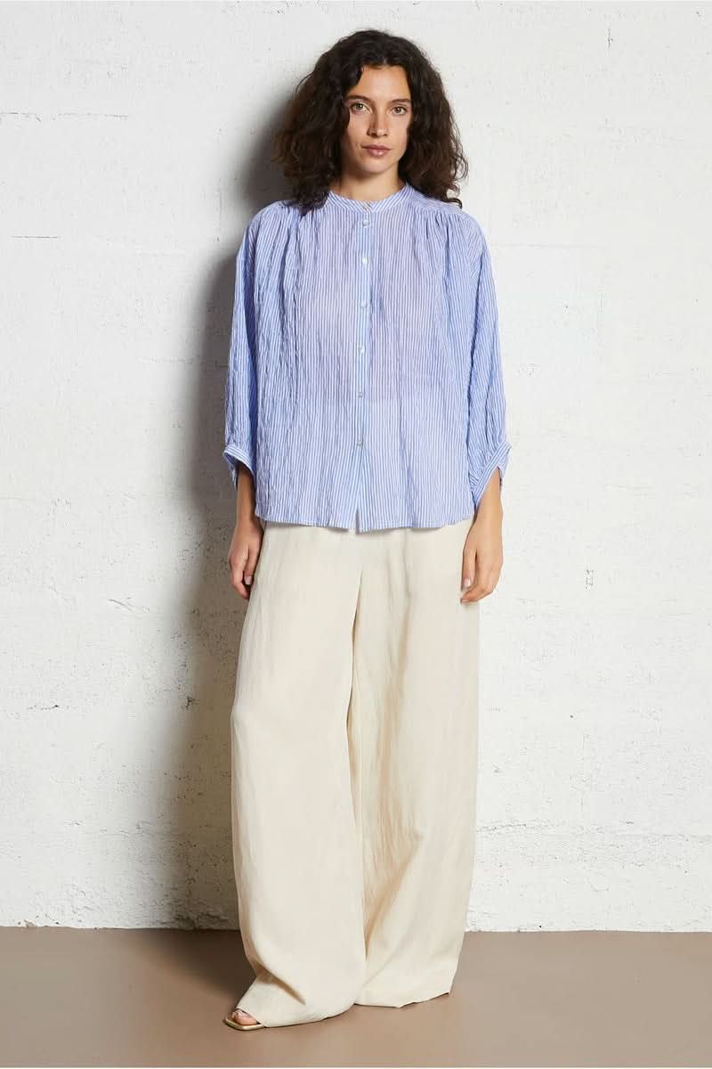 Femme portant une chemise intemporel bleue à manches longues et pantalon beige chic.