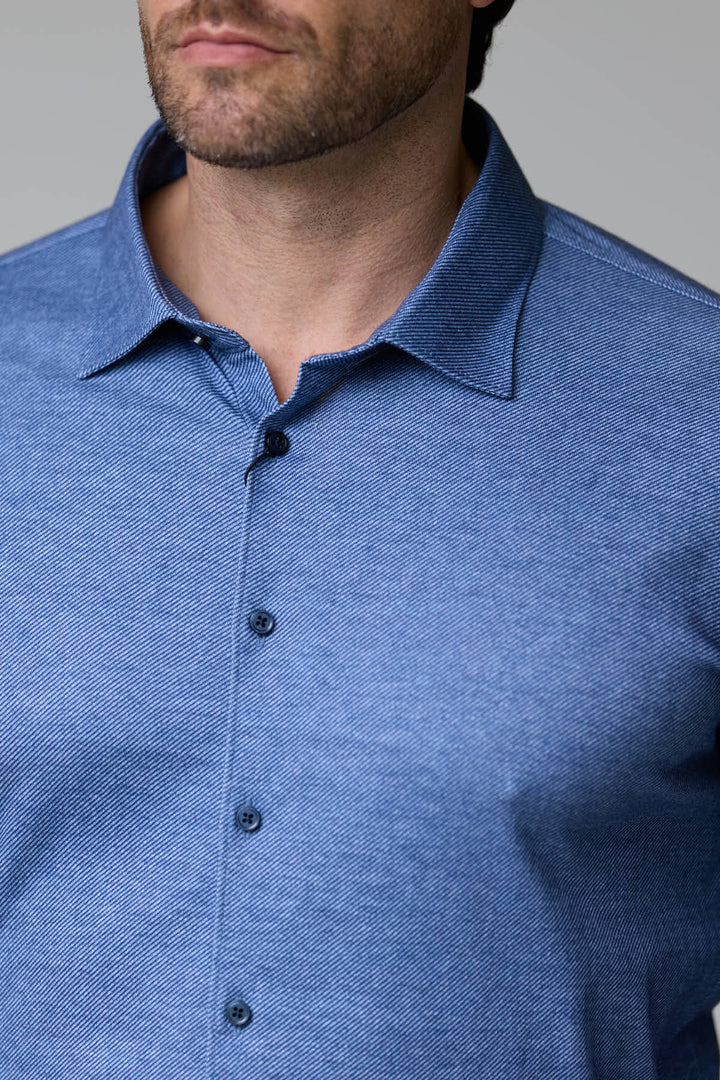 Homme portant une chemise jersey texturé bleu à manches longues avec col structuré, élégante et moderne, pour un look soigné.
