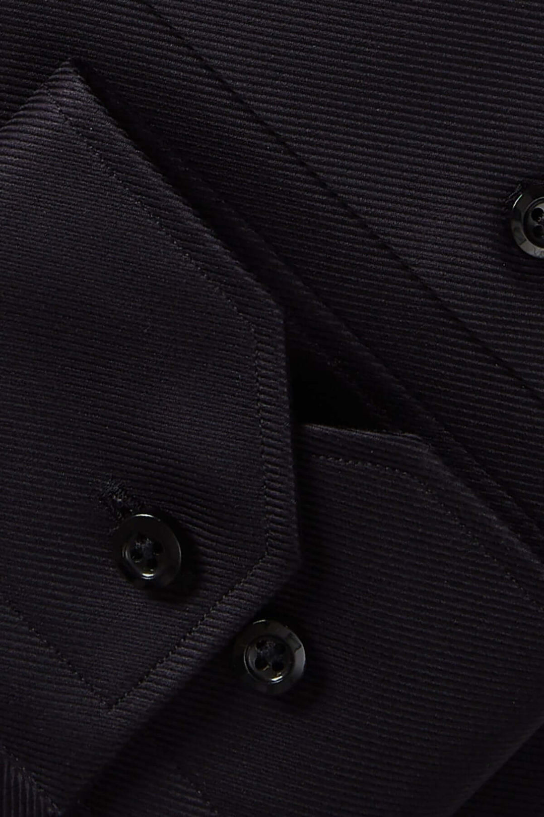 Détails d'une chemise moderne avec boutons noirs et tissu texturé, parfaite pour des occasions élégantes.