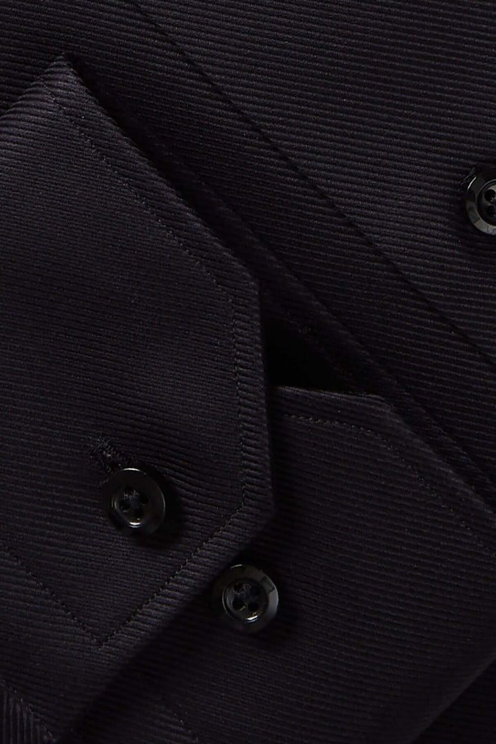 Détails d'une chemise moderne avec boutons noirs et tissu texturé, parfaite pour des occasions élégantes.