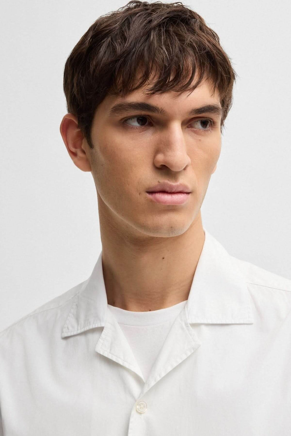 Homme portant une chemise oversize blanche à col camp, idéale pour un look décontracté et estival.