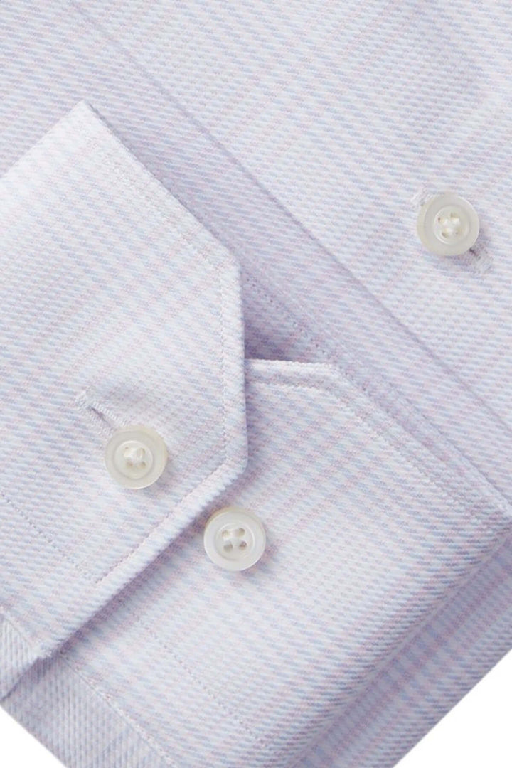 Détails de la chemise raffinée avec motif micro-carreaux et boutons nacrés sur les poignets ajustables.