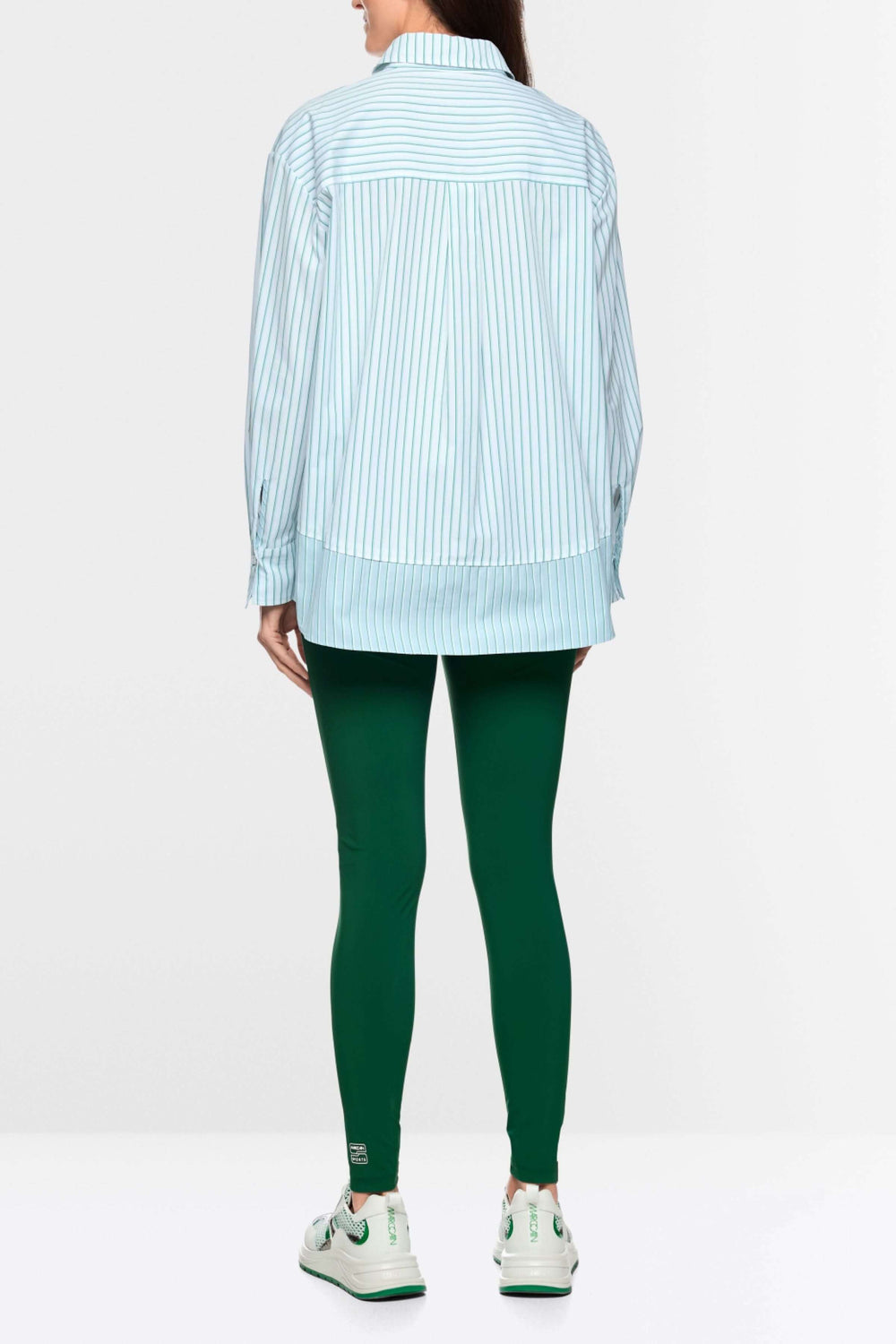 Vue arrière d'une chemise rayée en coton à coupe ample, portée avec un pantalon vert, mettant en valeur une allure moderne.