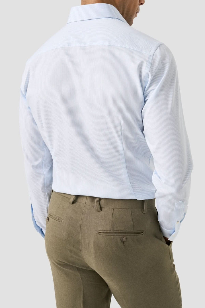 Homme portant une chemise rayée en coton et lyocell de dos, élégante, col italien structuré, confort quotidien, style moderne.