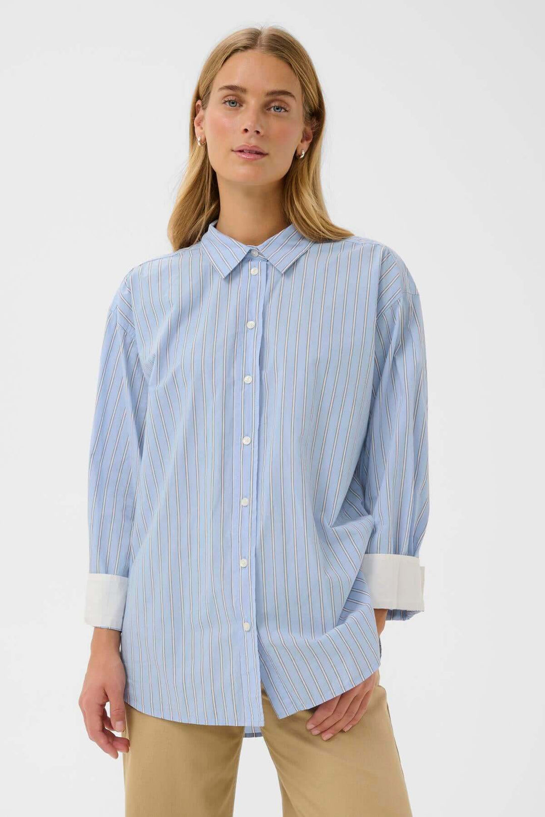 Chemise à rayures fines Savanna portée par une femme, style décontracté et moderne, poignets contrastants, longueur allongée.