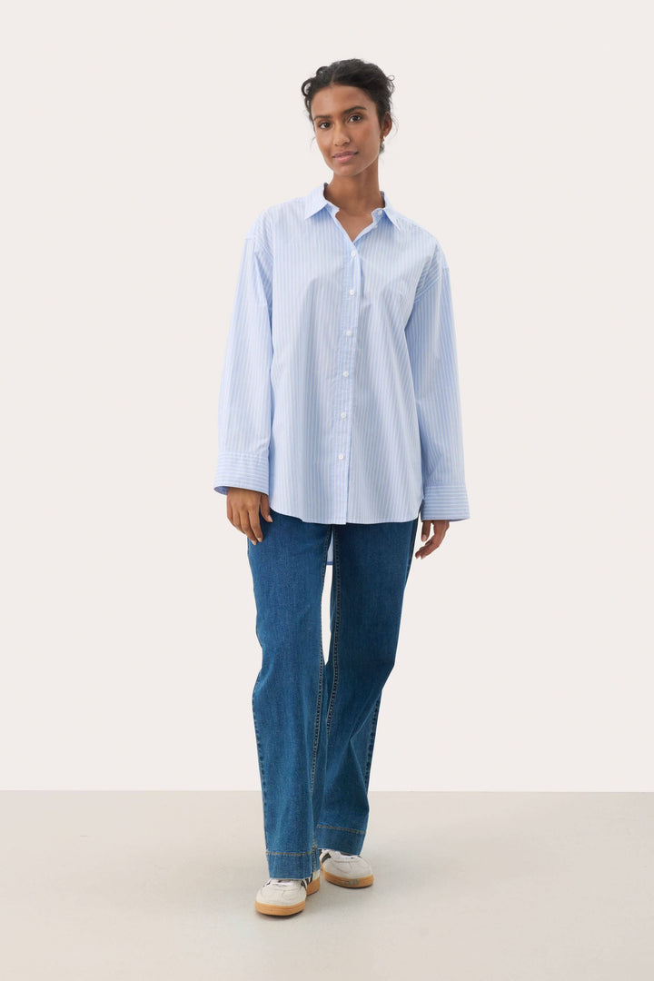 Femme portant une Chemise à rayures fines Savanna avec jean, offrant une allure moderne et décontractée idéale pour un look quotidien.