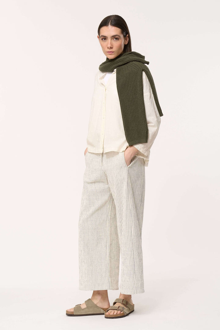 Modèle femme portant une chemise légère en coton, pantalon rayé, et un pull en tricot élégant.