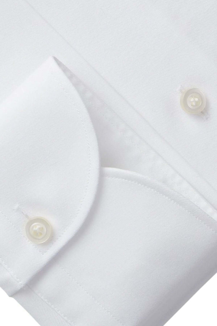 Détail d'une chemise blanche avec poignet droit et boutons nacrés, soulignant un style épuré et moderne.