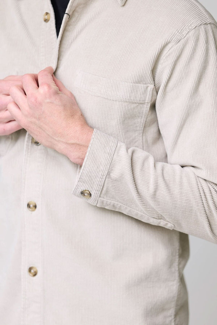 Homme portant une chemise sport en velours côtelé style surchemise avec boutons contrastants, vue de près sur les détails.