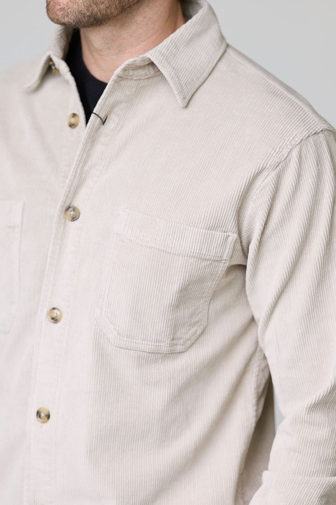 Homme portant une chemise sport en velours côtelé style surchemise avec poches plaquées et boutons contrastants.