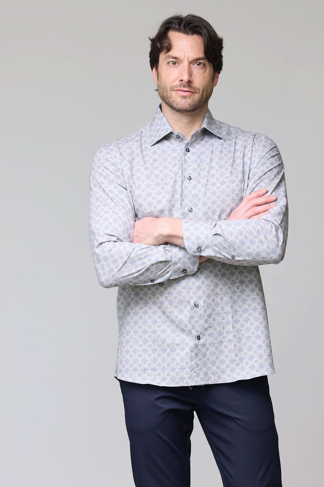 Homme portant une chemise sport à motif géométrique bleu pâle, coupe ajustée, col classique, boutons contrastants bleus nacrés.