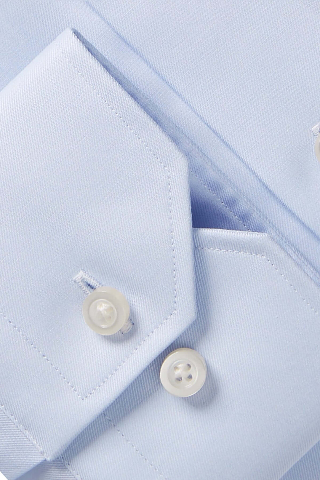 Détail d'une chemise contemporaine bleu avec col classique et boutons blancs, mettant en valeur le tissu texturé.