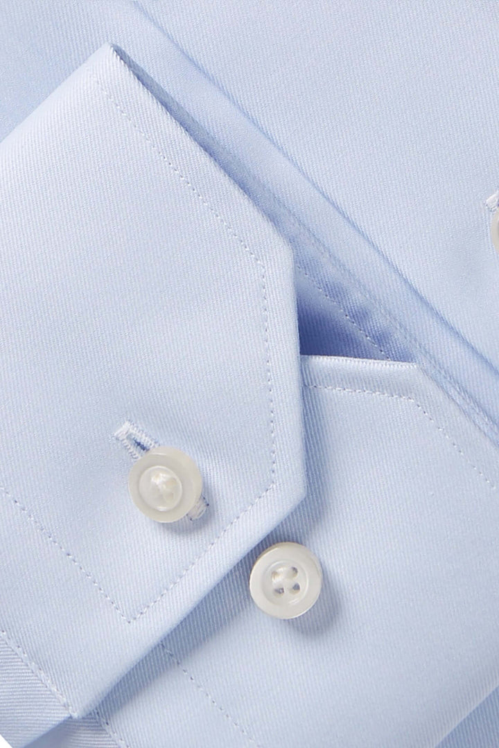 Détail d'une chemise contemporaine bleu avec col classique et boutons blancs, mettant en valeur le tissu texturé.