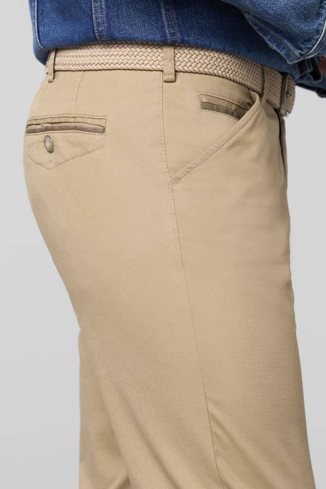 Pantalon chino beige ajusté avec ceinture en tressé, offrant une coupe moderne et élégante.