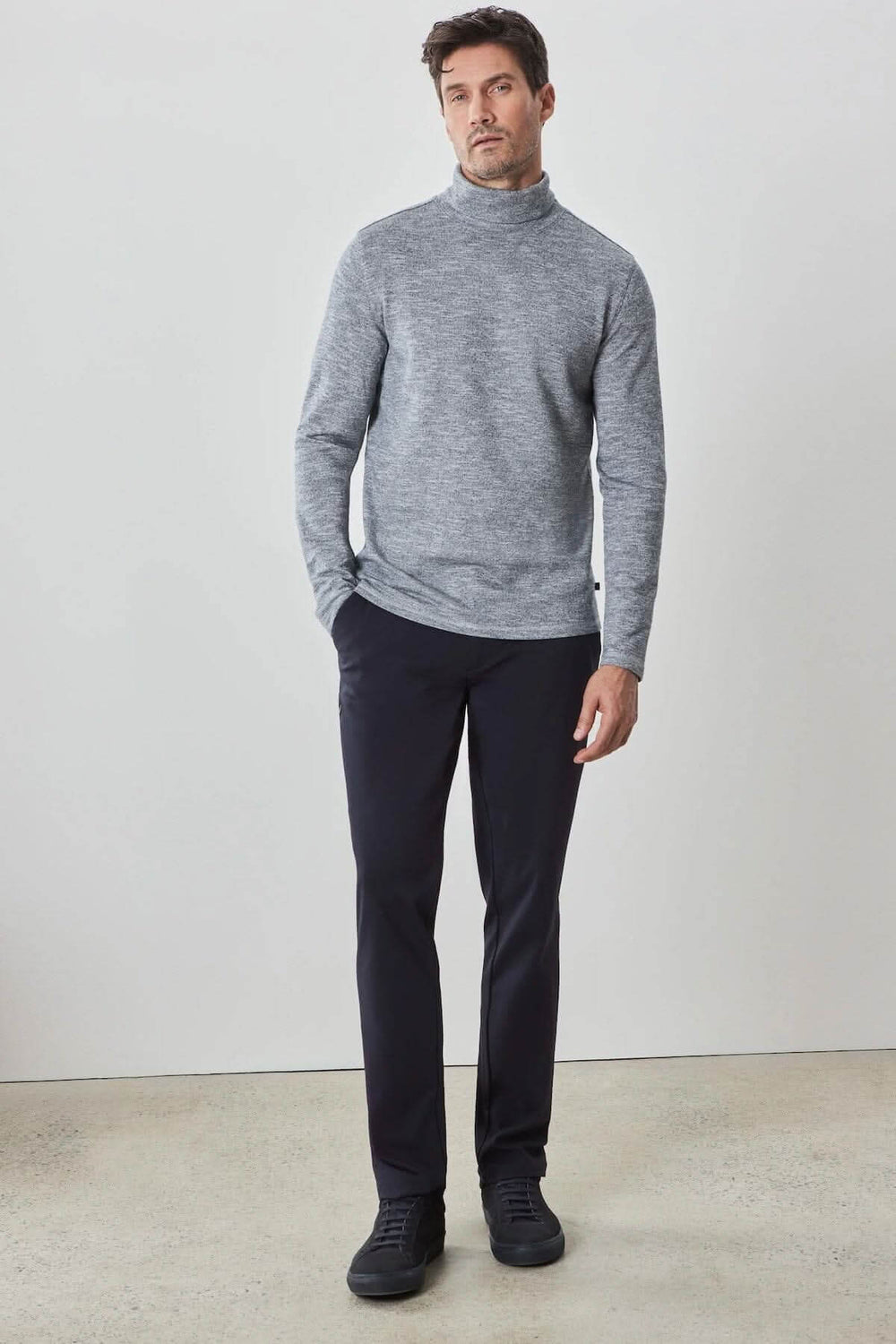 Homme portant un col roulé Crestwood gris en coton, associé à un pantalon noir, style moderne et confortable.