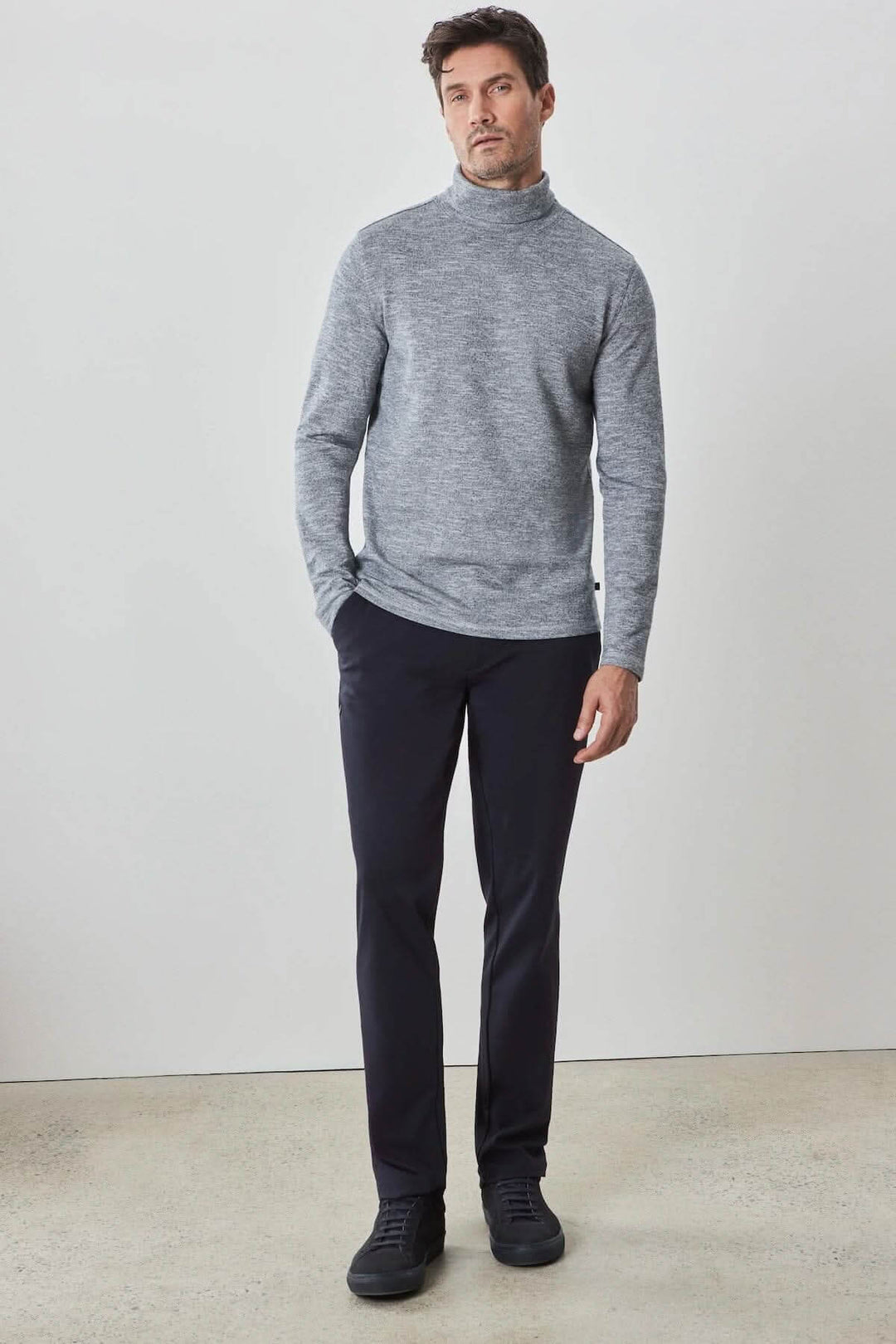Homme portant un col roulé Crestwood gris en coton, associé à un pantalon noir, style moderne et confortable.