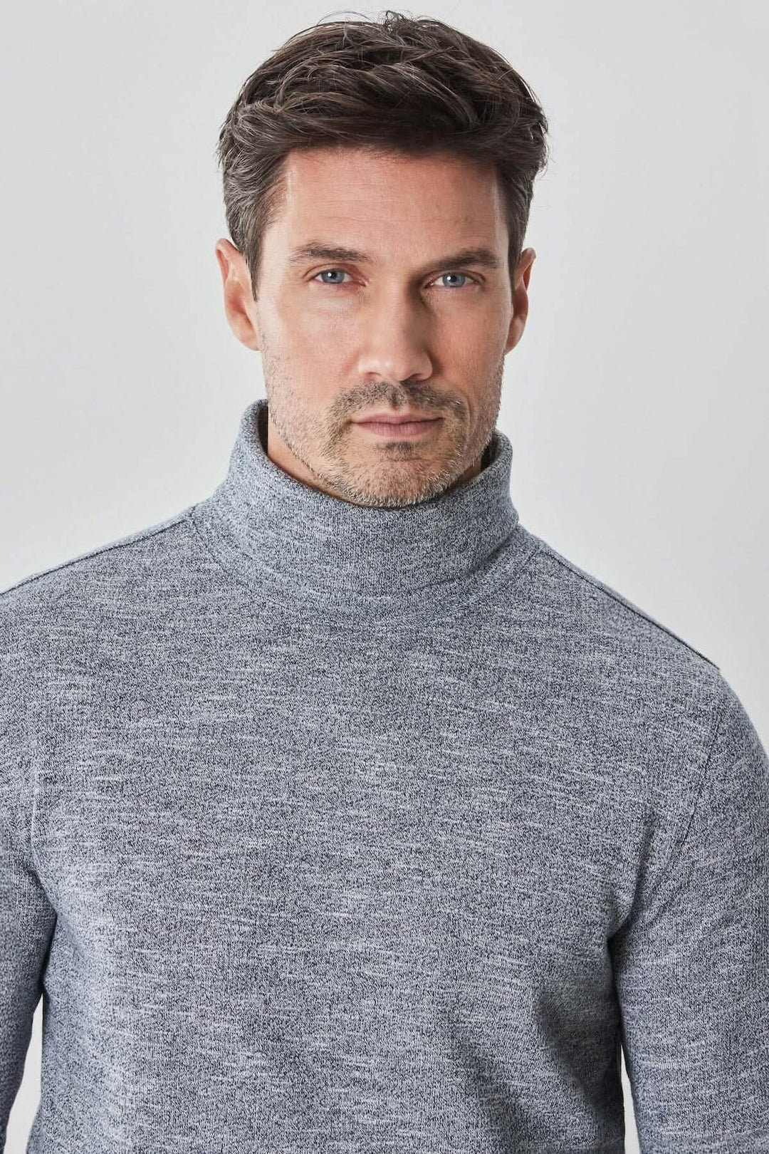 Homme portant un col roulé gris en coton, un vêtement confortable avec un look élégant et raffiné.